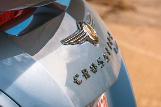Calgary, Alberta, Canada. Aug 28, 2026. Close-up detailed view of the chrome Chrysler winged emblem and Crossfire lettering on a blue car.