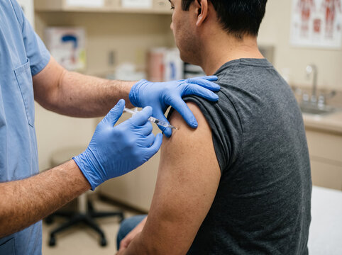 Healthcare Professional Vaccinating Adult Male Patient in Clinic Office