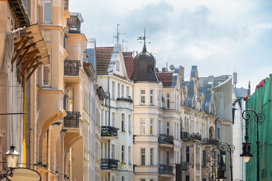 View of historic tenement houses with ornate facades, balconies, and a prominent corner tower under a bright sky in Poznan, Greater Poland Voivod, Poland.