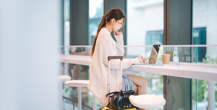 Beautiful young adult business asian woman using laptop work and travel using wireless digital technology at coffee cafe