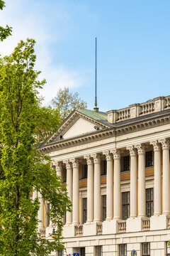 View of the Raczynski Library with its neoclassical columns and pediment framed by lush green trees in Poznan, Greater Poland Voivod, Poland.