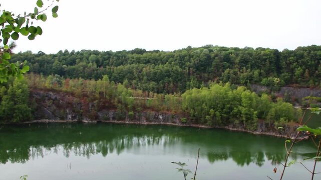 Old quarry lake or old mining pit was closed and flooded with freshwater as natural diving spot for tourism or hiking trail with idyllic quarry lake and impressive rock formations of quarrying mining