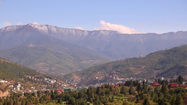 Thimphu valley with small town and forested hills below Himalayan mountain peaks, Bhutan