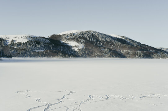 View of the frozen Lake Abant with animal tracks in the foreground and snow-covered mountains in the background in Dereceoren, Bolu, Turkiye.
