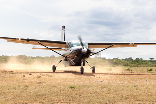 View of a Cessna Caravan aircraft taxiing on a dusty unpaved airstrip in the savanna of Zimbabwe.