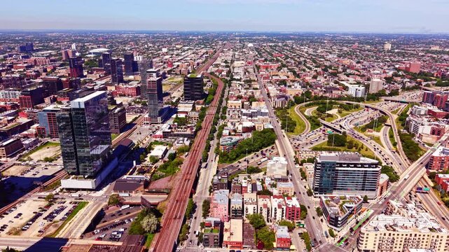 Context of sprawling urban highway and train tracks, Chicago. Elevated perspective of parallel railway lines, dense residential structures and distant horizon.