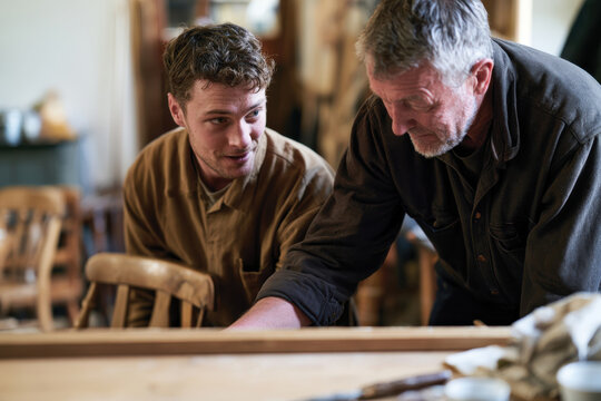 A young man enthusiastically learns from an experienced mentor, illustrating a moment of guidance in a workshop dedicated to handmade craftsmanship and artistic skill cultivation.