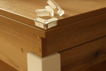 Fototapeta premium Soft protective corner guards are attached to sharp furniture edges to prevent child injuries. The image highlights toddler safety, household protection and simple measures used to reduce bumps and ac