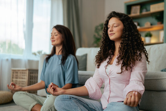 Mother and daughter meditating together practicing mindfulness at home
