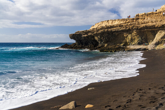 View of the black sand beach and dramatic limestone cliffs at Ajuy, Fuerteventura, Spain.