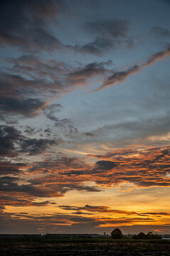 Vertical Dramatic Sunset Sky with Fiery Orange and Deep Blue Clouds.