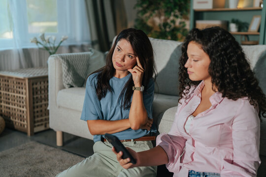 Mother and teenage daughter experiencing conflict over phone usage