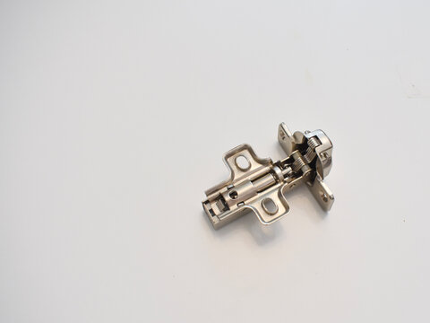 Close-up view of a single metal concealed cabinet hinge isolated on a white surface