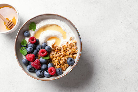 Granola bowl with greek yogurt, berries and honey for healthy breakfast.