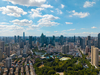 Naklejka premium A high angle aerial view shows the modern urban skyline of Wuhan China with many tall office buildings and green spaces under a bright blue cloudy sky