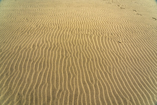 View of the sand ripples at Cofete beach with fine golden sand patterns formed by wind and tide in Cofete, Canary Islands, Spain.