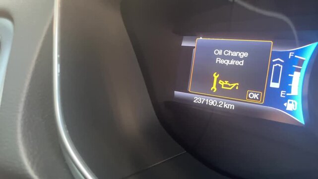 Car dashboard display showing oil change required notification with vehicle mileage and service icon illuminated, indicating maintenance needs for optimal vehicle performance. High quality 4k footage