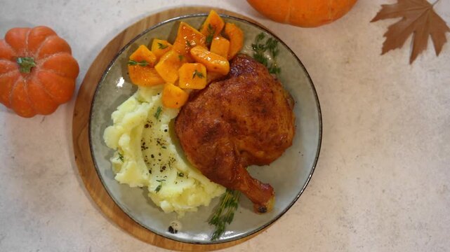 Roasted chicken quarter with glazed pumpkin, herbs and mashed potato, top view. Portion of festive autumn meal for Thanksgiving. Healthy seasonal food.