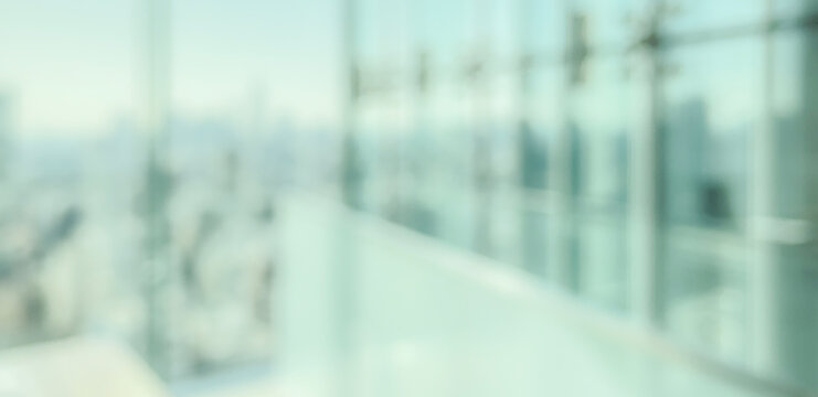 A blurred view from a modern glass building showcasing a city skyline. The atmosphere conveys a sense of height and urban environment.