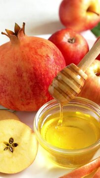 Happy Rosh Hashanah. Jewish New Year holiday concept. Honey dipper in a bowl with honey, next to apples, shofar horn and pomegranates.