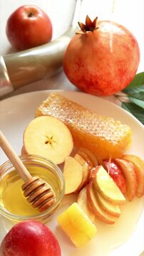 Happy Rosh Hashanah. Jewish New Year holiday concept. Honey dripping to apples slices, next to apples, shofar horn, honey bowl and pomegranates.