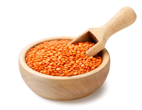 Red lentils in a wooden bowl with a spatula on a white. Isolated