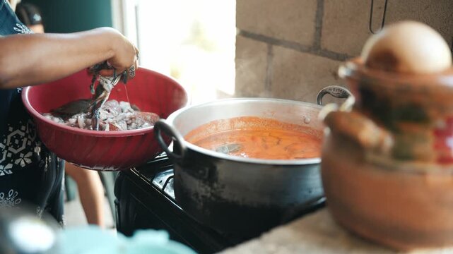Mexican family preparing a traditional seafood dish with crabs and fish in a rustic kitchen