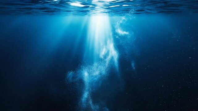 Underwater view of sunlight penetrating ocean water with a mysterious cloud of particles, creating a serene and captivating scene.
