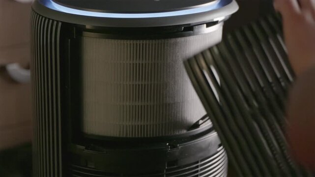 Hands installing new paper HEPA filter into air purifier
