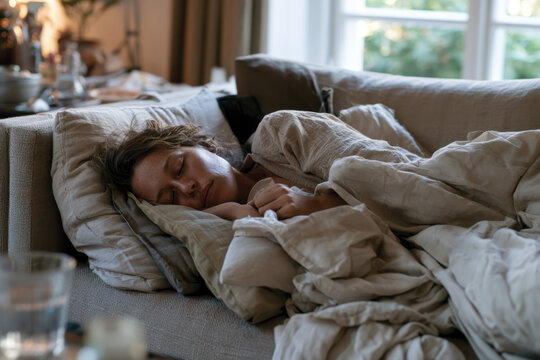 A woman peacefully sleeps on a soft sofa, embodying relaxation and tranquility in a cozy setting, showcasing the necessity of rest and comfort in a balanced life.