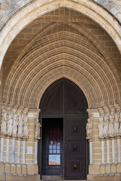 View of the ornate gothic portal of the Cathedral of Evora featuring intricate stone sculptures and a large wooden door in Evora, Distrito de Evora, Portugal.