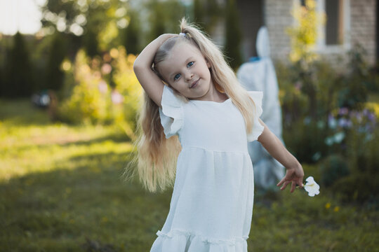 a cute five-year-old girl in a white dress is playing in a green summer garden. happy childhood