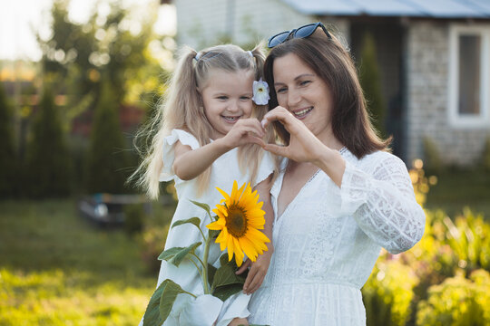 a cute five-year-old girl with mother in a white dress are playing in a green summer garden. happy childhood