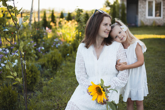a cute five-year-old girl with mother in a white dress are playing in a green summer garden. happy childhood
