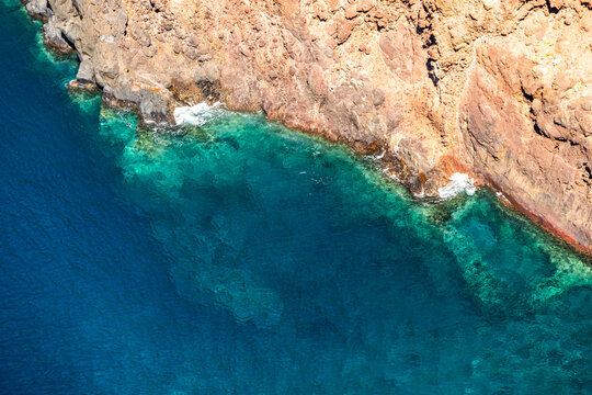 Stunning crystal clear turquoise ocean water meets rugged volcanic cliffs at Ponta de Sao Lourenco in Madeira under bright sunlight with scenic coastal vibes.