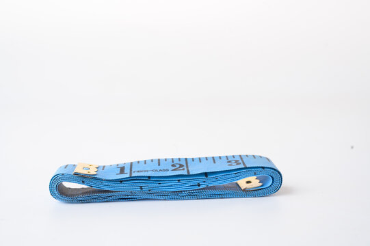 A blue fabric measuring tape is coiled neatly on a white surface, showing numbers and measurement markings.