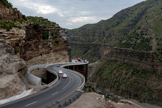 View of the winding Fort Munro Road carved into the steep rocky mountainside with vehicles traveling along the cliffside in Fort Monroe, Punjab, Pakistan.
