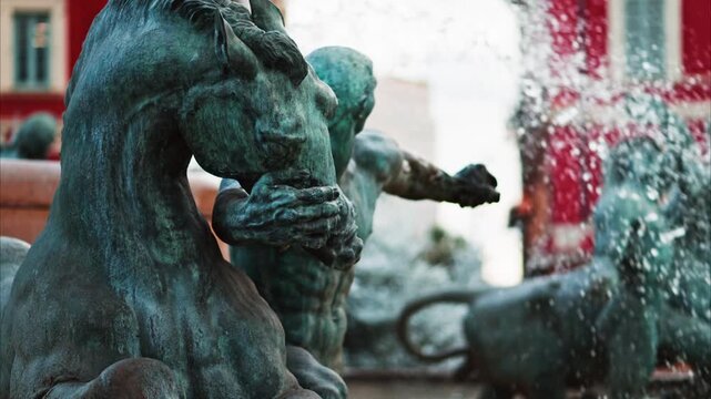 Close-up shot of bronze fountain sculptures depicting horses and human figures with splashing water.