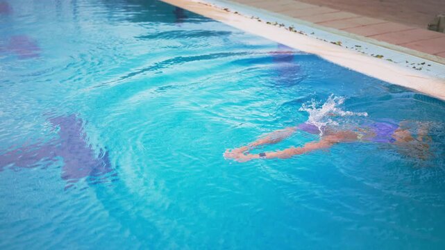 Athletic female swimmer training in outdoor pool,pushing off wall and gliding underwater before start freestyle stroke,demonstrate swimming technique,endurance,discipline, competitive sports training