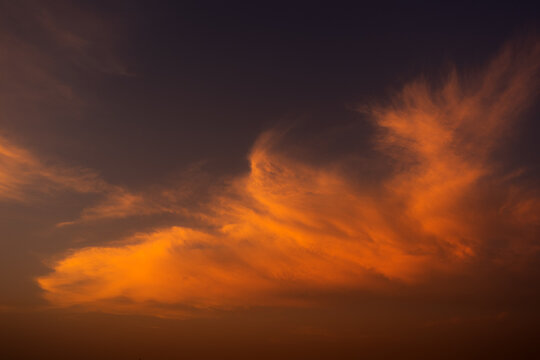 View of a vibrant sunset with glowing orange clouds against a dark twilight sky in Jahanian, Punjab, Pakistan.