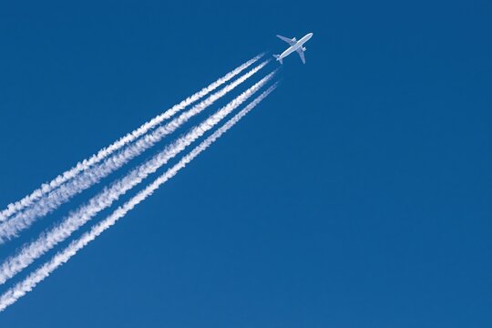 The Airplane Soaring Through a Clear Blue Sky with White Contrails