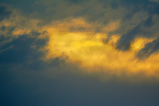 View of dramatic golden sunlight breaking through dark storm clouds in the sky over Jahanian, Punjab, Pakistan.
