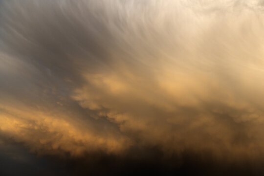 View of dramatic golden storm clouds illuminated by the setting sun over the landscape of Jahanian, Punjab, Pakistan.
