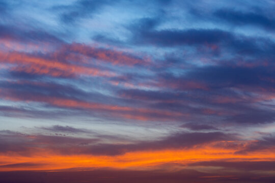 View of vibrant sunset sky with layers of orange, purple, and blue clouds over the horizon in Jahanian, Punjab, Pakistan.