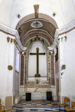 View of the altar with a prominent black cross inside the historic Igreja de Nossa Sr.a da Nazare, featuring ornate architectural details and a checkered floor in Elvas, Portalegre District, Portugal.