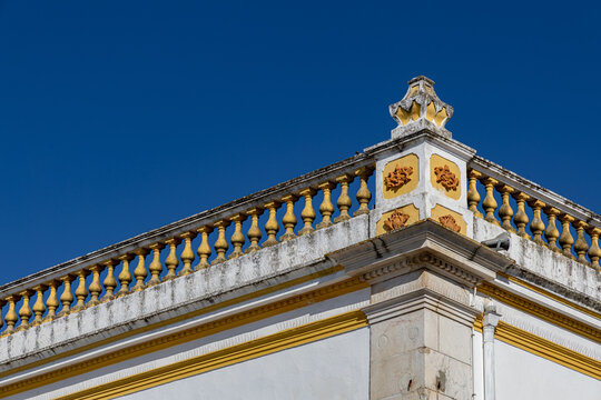 View of the decorative yellow balustrade and ornate corner pillar of a historic building against a clear blue sky in Elvas, Portalegre District, Portugal.