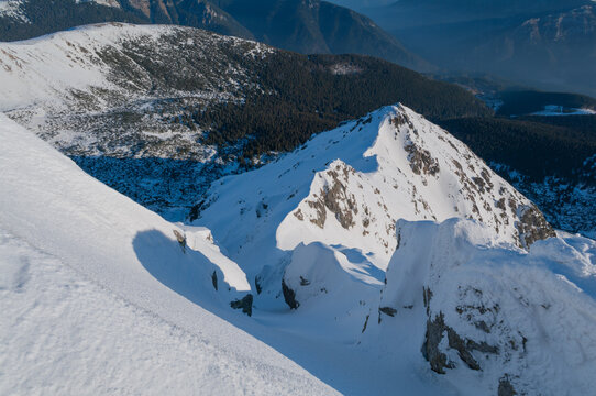 View of the snow-covered peak of Dumbier mountain with rocky ridges and deep shadows in the winter landscape of Nizke Tatry, Zilina Region, Slovakia.
