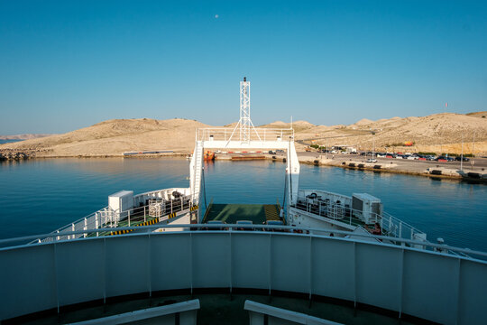View of Misnjak Ferry Port with a ferry approaching the rocky coastline under a clear blue sky in Barbat na Rabu, Primorsko-goranska zupanija, Croatia.
