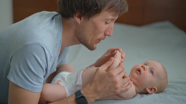 Father talking to his three month old baby son and kissing his hands.