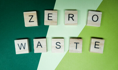 Fototapeta premium Wooden letter tiles spelling 'Zero Waste' on a green and light green background, emphasizing sustainability and eco friendly practices.